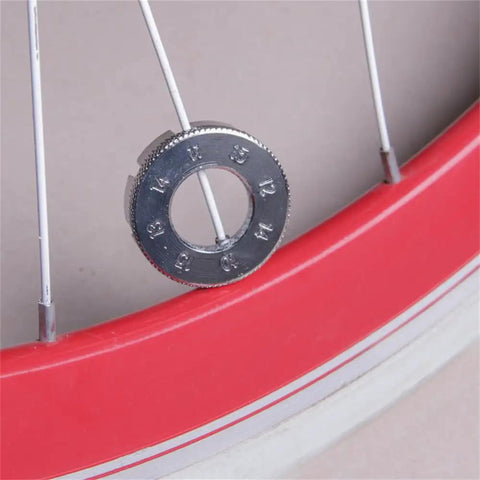 Close-up of one Two Pack Spoke Wrenches In Hardened Steel, resting on a bicycle wheel for rim truing and spoke adjustments.