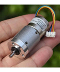 12V DC Full Metal Planetary Gearbox Reducer for Stepper Motors held in hand, showing wires and D shaft, suitable for CNC and robotics.