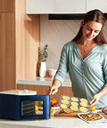Digital Electric Food Dehydrator With Four Stackable Stainless Steel Trays And Precision Temperature Controls featuring a user loading fruits.
