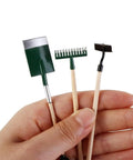 Hand holding 1:12 Dollhouse Mini Garden Tool Set With Shovel Hoe And Pitchfork, Tiny Hand Planting Tools, Wood Handles, Realistic Decor