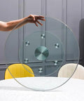 Super Smooth Tempered Glass Lazy Susan For Dining Table 360 Degrees Turntable held above a table, showcasing its round design and base.