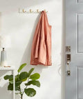 Swoop Up Fresh Wall Mounted Coat And Hat Rack Featuring Four Sleek Gold Dual Hooks On A Crisp White Base with a jacket hanging.