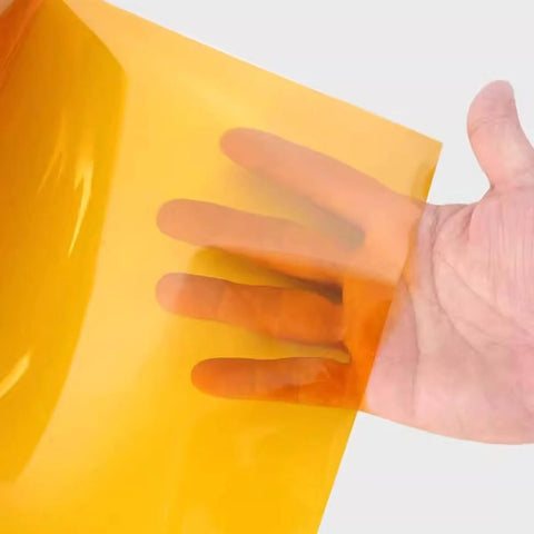 Hand holding translucent golden Non Adhesive Polyimide Film Sheet 200mm x 300mm High Temperature Resistant PI Film For Electrical Insulation 0.025-0.25mm Thick
