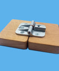 Front view of a silver zinc-alloy adjustable torque folding table hinge mounted on two wooden blocks; screws visible