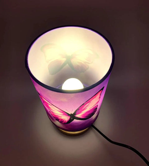 Top view of Chic Purple Butterfly Table Lamp With Wooden Base Bedside Light, glowing with included 3W LED bulb.
