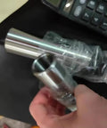 Close-up of a silver steel Morse taper reducing adapter sleeve held by hand; for lathes and drill presses