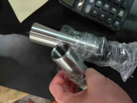 Front view of a silver Morse taper adapter reducing drill sleeve, held in hand.