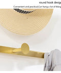 Built Different Three In One Entryway Hall Tree Featuring Upholstered Shoe Storage Bench with gold round coat hook and straw hat.