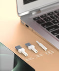 32-in-1 electronics cleaning kit components, front view with white handles and blue bristles beside laptop and smartphone.