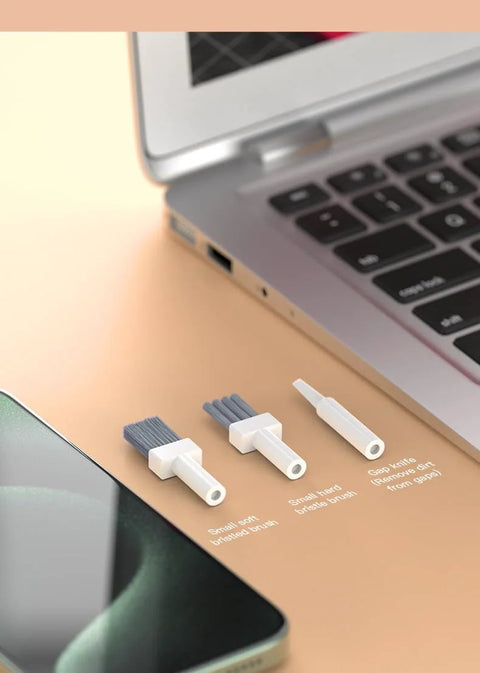 32-in-1 electronics cleaning kit components, front view with white handles and blue bristles beside laptop and smartphone.