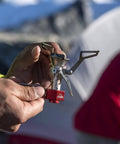 Hands holding ultralight folding camping stove that fits in your pocket, boils 1 liter in about 3.5 minutes, adjustable flame.