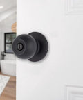 Transitional Privacy Door Knob Set In Matte Black For Exterior Doors With Lock, installed on an open white door