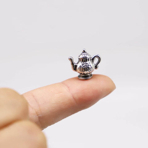 Close-up of Hinge Head Silver Tea Set Door Decor Toppers Three Pack Magnetic Miniature Teapot And Cup Figurines For Doors on fingertip