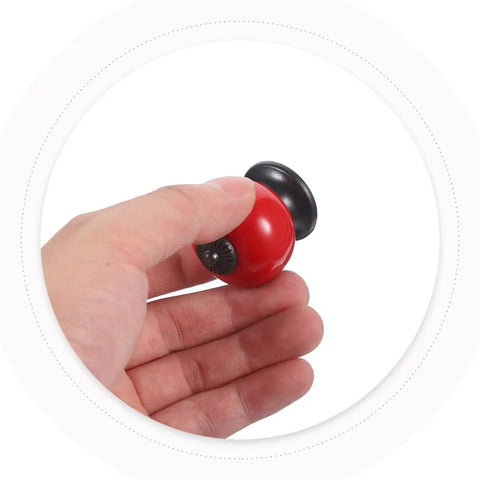 Hand holding a Slick Red Ceramic Cabinet Knob, 1.5 inch round, designed for kitchen cupboards and dressers.