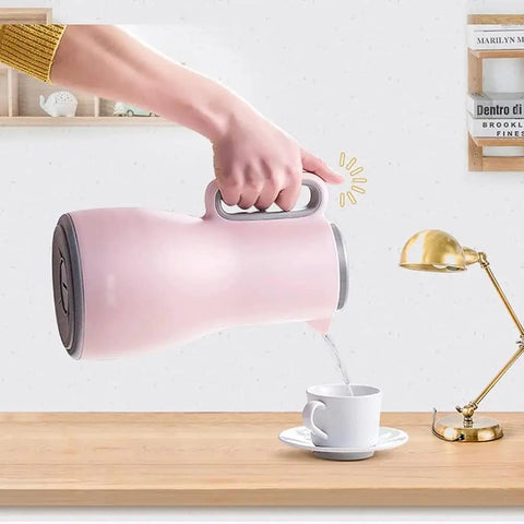 Grab And Go Kickass Vacuum Insulated Travel Thermos With Secure Silicone Lid pouring into a cup on a wooden table.