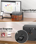 Front view of Genmitsu Kiosk 10W desktop laser engraver with acrylic enclosure on a wooden desk.