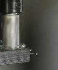 Close-up of 5/8 x 1 in high-speed steel annular cutter in drill press chuck, cutting metal with chips