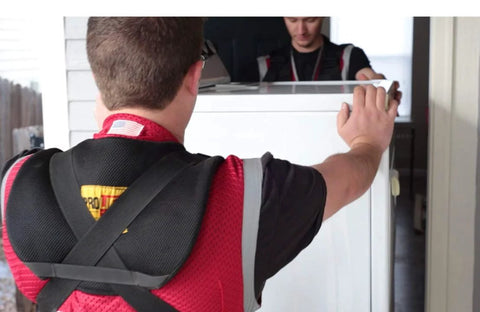 Nielsen Shoulder Dolly 3500 two-person lifting straps in use; movers carry a large white appliance.