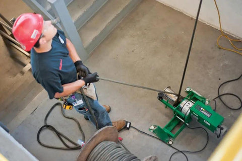 Electrician using Greenlee Ut10 Pulling Package with heavy duty floor mount for wire handling in a commercial setting.