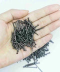 A hand holding Black Round Head Decorative Nail Set For Dollhouses And Furniture, 25mm Miniature Wood Screws, Old School Antique Black Iron Finish.