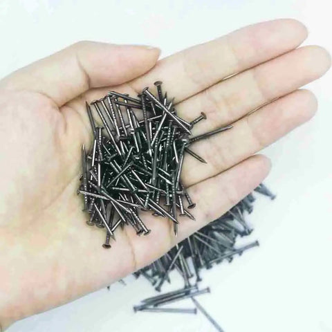 A hand holding Black Round Head Decorative Nail Set For Dollhouses And Furniture, 25mm Miniature Wood Screws, Old School Antique Black Iron Finish.