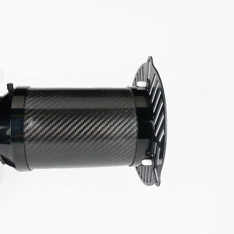 Carbon fiber cylindrical object with vented end cap, close-up angle on smooth textured surface and slotted design.