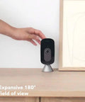 Person adjusting Indoor WiFi Security Camera With 1080p HD Video, 180 Degree Field Of View, on wooden table.