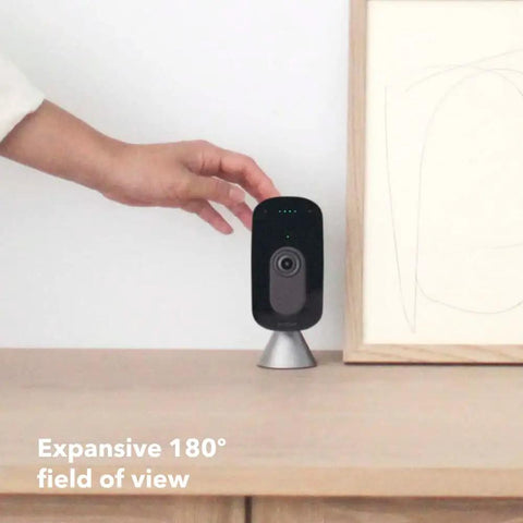 Person adjusting Indoor WiFi Security Camera With 1080p HD Video, 180 Degree Field Of View, on wooden table.