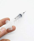 Person holding a single syringe from the Three 10cc Syringe SMT SMD PCB Solder Flux Paste Adhesive Glue Liquid Dispenser Set With Needle Caps