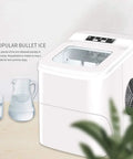 Compact Electric Ice Cube Maker Countertop Portable Machine That Blasts Ice In Six Minutes Flat With Ultra Quiet Operation, white ABS design, water pitcher nearby.