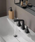 Matte black widespread bathroom faucet on a 3 hole vanity sink with water flowing.