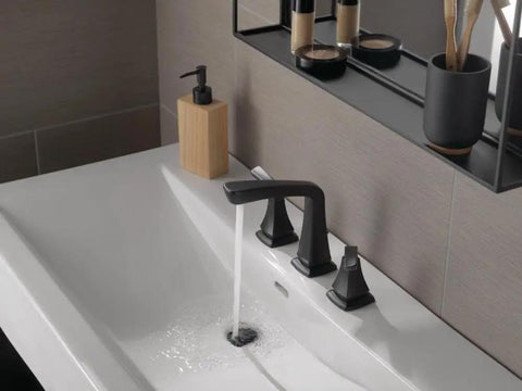 Matte black widespread bathroom faucet on a 3 hole vanity sink with water flowing.