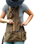 Person wearing Rugged Waxed Canvas Garden Tool Apron With Padded Shoulders And Twelve Pockets For Tools And Phone Built To Last