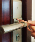 Hand using No Touch Door Opener Tool With Stylus And Button Pusher on door handle, rose finish, multifunctional, touch-free entry helper.