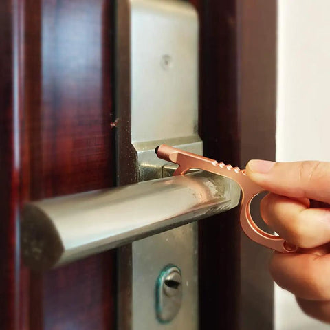 Hand using No Touch Door Opener Tool With Stylus And Button Pusher on door handle, rose finish, multifunctional, touch-free entry helper.