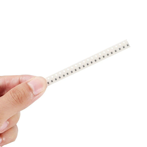 Hand holding a strip from the 0805 SMD Resistor Kit With 1500 Pieces 60 Values From 0 Ohm To 10 Mega Ohm One Percent Tolerance Great For DIY Electronics 0.125 Watt Rating 0805 Chip Resistors Surface Mount Assortment