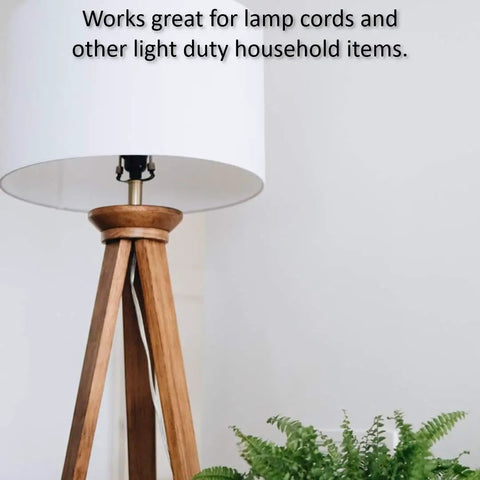 Table lamp with wooden tripod base beside a plant, highlighting use for light duty household items like lamp cords.