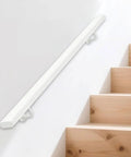 Heavy Duty Wrought Iron Stair Handrail Indoor Outdoor Rust Resistant Custom Length Grab Rail Built Tough With Heavy Gauge Steel Secure Step Railing For Home And Business Use mounted on a wall beside wooden stairs.