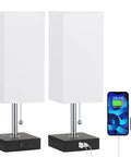 Set Of 2 Bedside Lamps With Dual USB Ports For Fast Phone Charging, Nightstand Table Lamps With White Fabric Shade and charging devices.