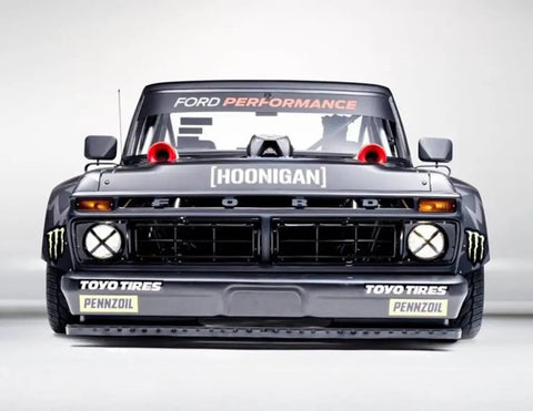Front view of a modified Ford truck with racing decals, including Toyo Tires and Pennzoil, signed with 'Hoonigan' on the grille.