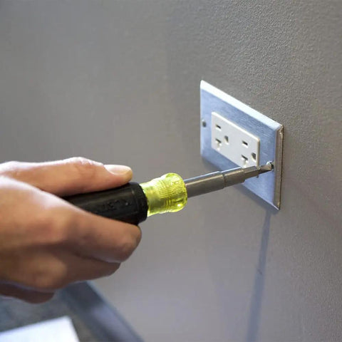 Using All-In-One Screwdriver Kit With 11-In-1 Multi-Bit Driver And 6-In-1 Stubby to tighten wall outlet screw, hand tool in action.