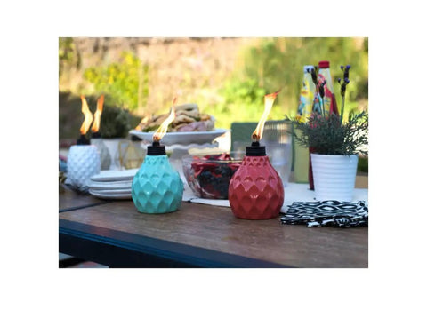 Decorative Glass Table Torch With Durable Fiberglass Wick And Metal Snuffer Creates Cozy Ambience For Dining Or Desk Decor Burns Up To Six Hours Per Fill A Thoughtful Holiday Gift For Family And Friends on an outdoor table.