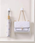 Heavy Duty Adhesive Wall Hooks For Bathroom And Kitchen Built Tough With Super Grip Oil Resistant Plastic Surface Mounts Zero Hole Punch Needed Fully Waterproof Set Of Three White Units holding a white handbag and umbrella.