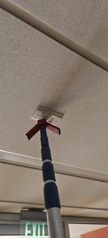Rock Solid Dual Magnet Smoke Detector Test Tool For Fire Safety Systems With Quick Pole Thread Adapter and Duct Activation Features in use on ceiling.