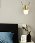 Brass Antlers Wall Sconce With E27 Socket Creates A Cozy Top Tier Glow For Bedrooms And Living Rooms Featuring Easy Peasy Install Vibes. Stylish lamp mounted beside a bed.