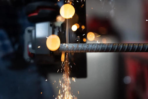 Close-up of 4-1/2-inch cut-off wheel on angle grinder cutting metal rod with sparks.