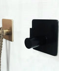 Rock Solid Black Stainless Steel Adhesive Wall Hook For Coats Towels And Umbrellas With No Hassle Peel Stick Mount on wall.