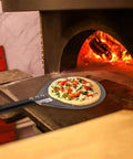 9 Inch Round Perforated Aluminum Pizza Peel With Detachable 40 Inch Handle Lightweight Yet Durable Pizza Turner For High Heat Ovens Outdoor Pizza Oven Accessories For Easy Slide And Turn Pro Grade shown with pizza in oven.