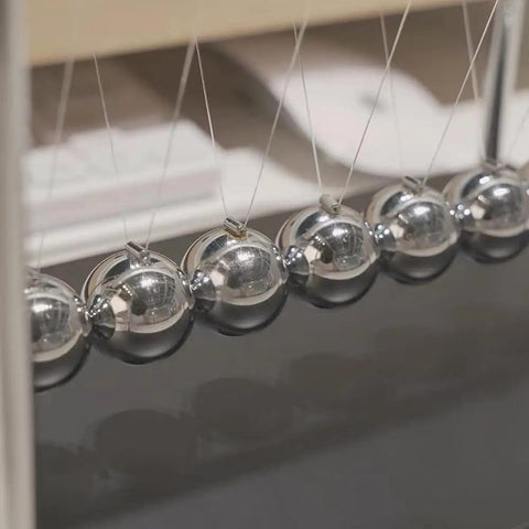 Close-up of 7 Ball Desk Pendulum Cradle With Glass Base And Stainless Steel Balls, Classic Office Desk Toy For Classroom Demos.