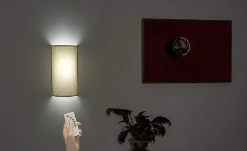 Hand using remote for Fabric Wall Sconce Lighting 11.8 Inch Tall Two Pack With Remote No Fuss 3 Color Modes Natural White Cold White Warm